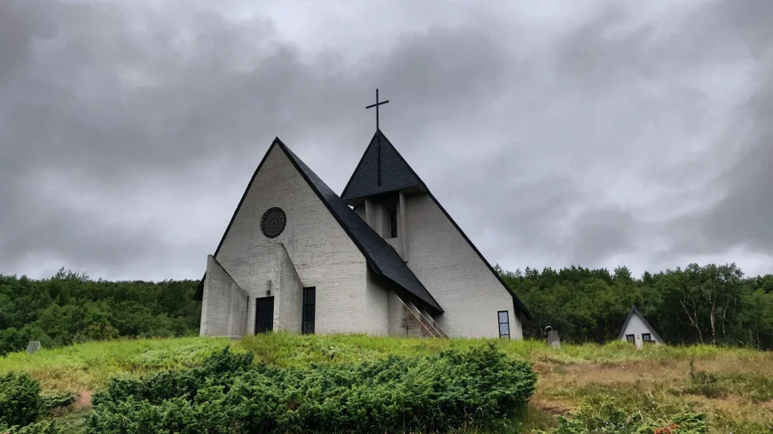 Kirche am Olavsweg unter dramatischem, wolkenverhangenem Himmel